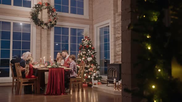 Whole Family Talking and Eating at the Table on Christmas Eve Filmed From Afar