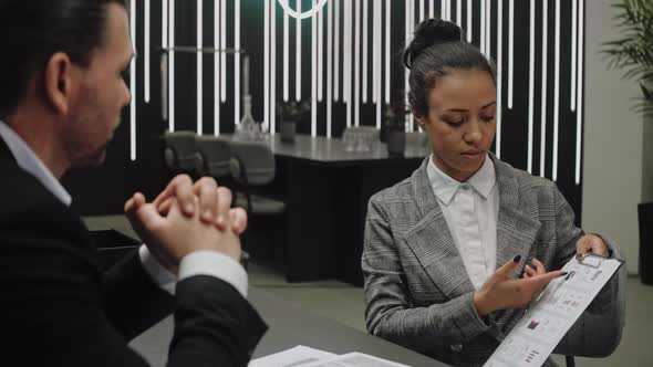 Woman Shows Business Graphics on Paper to Her Chief in Modern Office