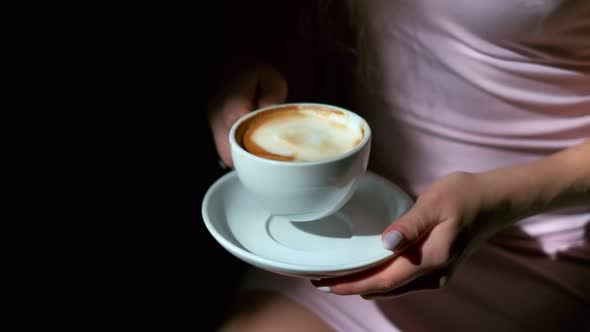 Closeup of Cup of Black Coffee and Saucer in Female Hands