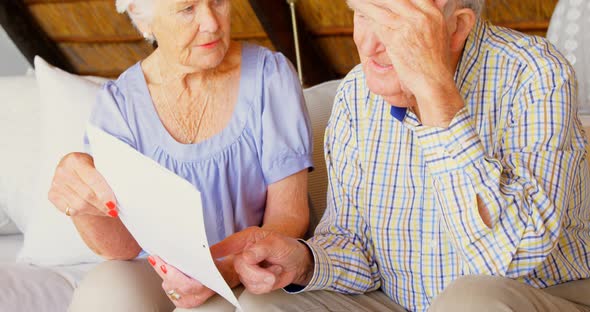 Front view of senior Caucasian couple discussing over bills with each other in a comfortable home 4k