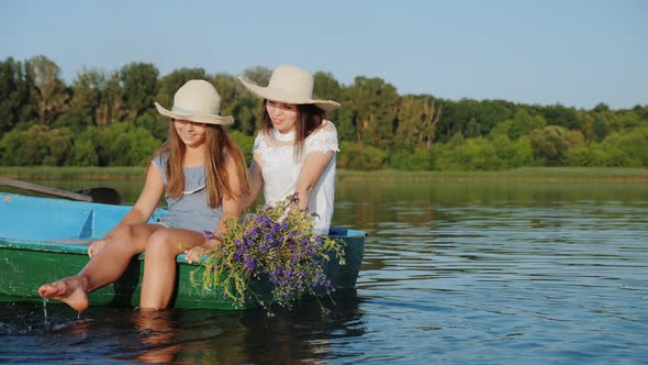 Mom with Daughter in Hats Sail in a Wooden Boat