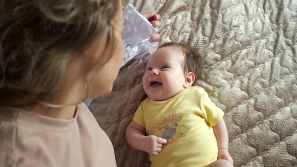 Happy Young Mother Plays with Excited Laughing Baby Daughter