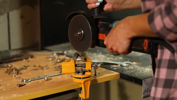 Woman locksmith works with grinder machine, fly bright sparks