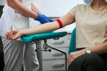 Lab technician placing a tight elastic band around the patient limb