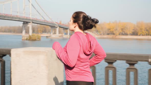 Chubby female doing running workout in industrial city park