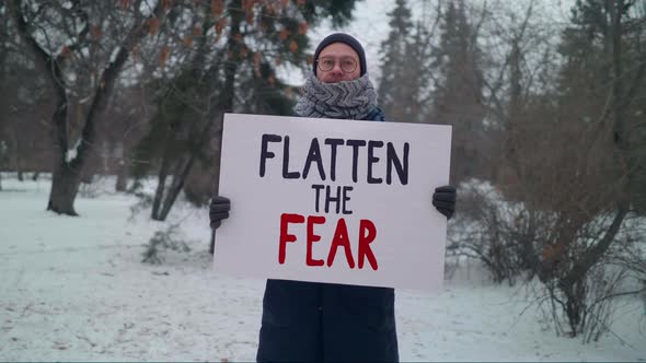 Male protester drawing attention to media lies with a sign Flatten the Fear