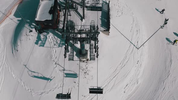 Aerial Top View of Ski Lift for Transportation Skiers on Snowy Ski Slope. Drone Flies Over Chair