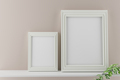 Two white portrait picture frame mockups on beige wall. 3d render - PhotoDune Item for Sale