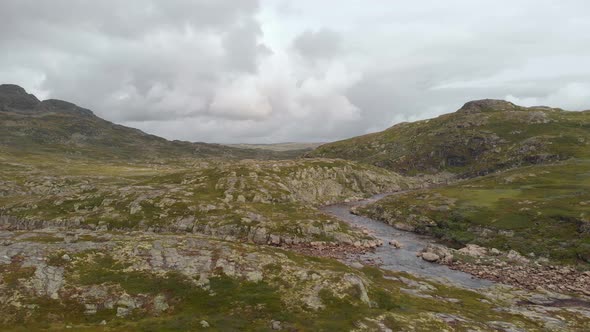 Rocky green Norway Hardangervidda valley and river, aerial side truck view