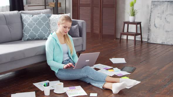 Young woman works with documents using a laptop at home.