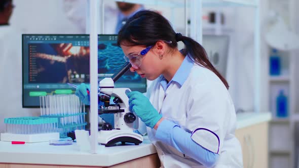 Scientist Woman with Microscope Examining Samples and Liquid