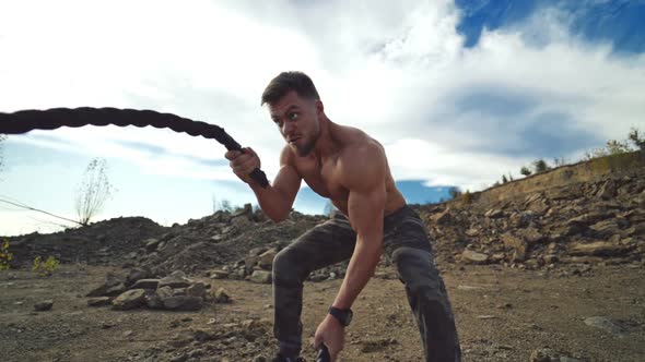 Cross power training. Concentrated sportsman exercises outdoors. Young shirtless muscular man traini