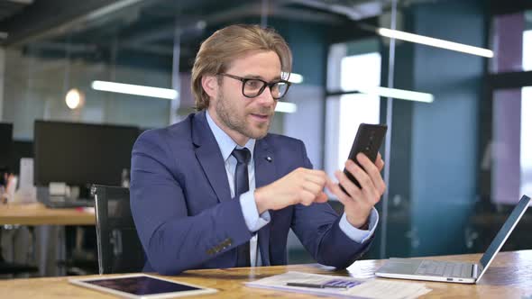 Excited Businessman Celebrating Success on Smartphone