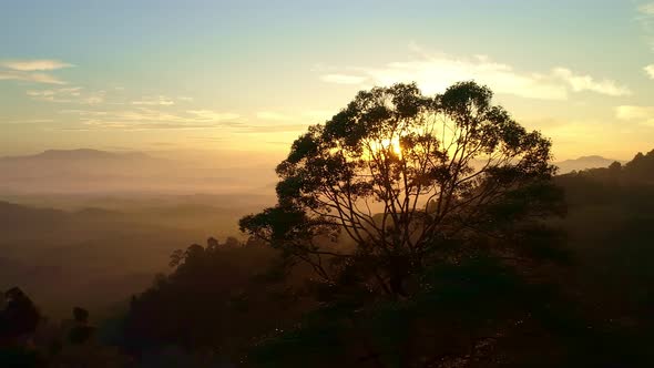 Drone flying through the fog above mountain peak Beautiful light sunrise