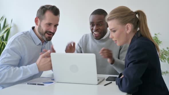 Cheerful Business People Celebrating Success While Using Laptop in Office