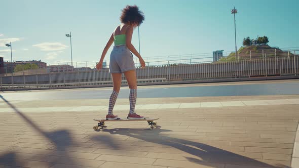 Beautiful young woman cruising around the city with her longboard.