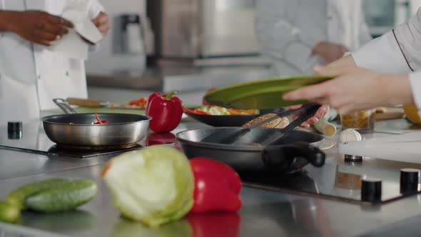 Professional Cook Preparing Beef Steak in Frying Pan on Kitchen Stove