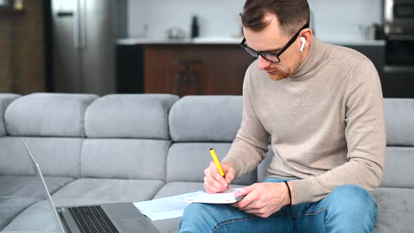 Serious Businessman with a Laptop is Taking Notes