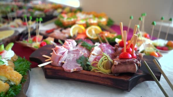 A set of meat canape snack in a wooden plate on a buffet table