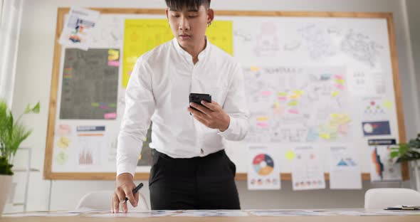 Asian man checking to task and holding smartphone