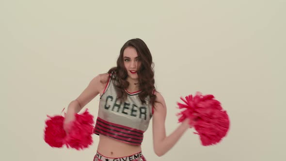 A Girl Dancing a Jubilant Dance with Pompoms in the Studio on a White Background