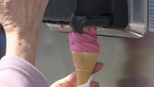 Super slow motion shot of female ice-cream vendor preparing pink soft ice cream in summer