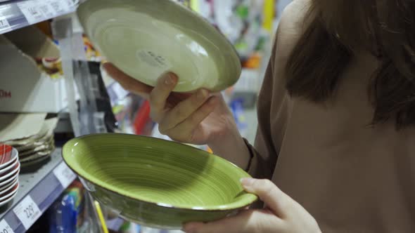 A Young Woman in a Store Choosing Dishes