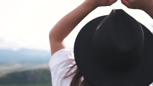 Attractive Brunette in a Hat and White Shirt Is Enjoying Nature in the Mountains. Hat and Hair