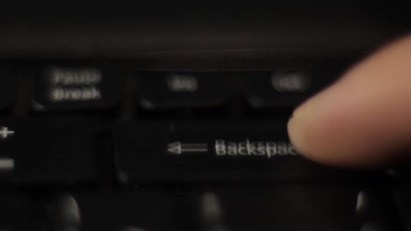 The Finger Presses the Backspace Button on the Keyboard. Close-up.
