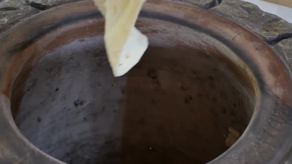 the Hands of an Oriental Baker Take Out an Armenian Thin Lavash Baked in Tonir with the Help of a