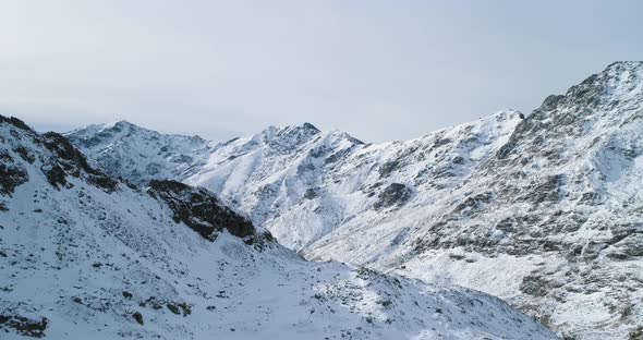 Forward Aerial Top View Over Winter Snowy Mountain Rock Peaks