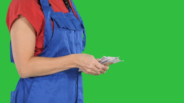 A woman in a workers clothes counts money on a Green Screen