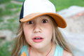 A surprised girl in a baseball cap is looking at the camera. - PhotoDune Item for Sale