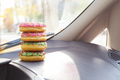 A tower of four donuts with multicolored icing and sprinkles in the car. Snack on the way to work. - PhotoDune Item for Sale