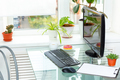 Computer and tablet with a blank sheet of paper on a glass table near a window with indoor plants. - PhotoDune Item for Sale