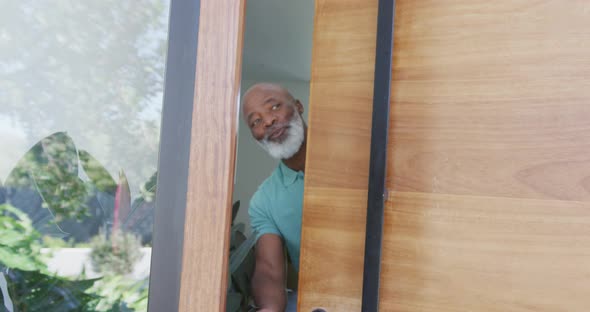Portrait of happy senior african american man opening door at retirement home