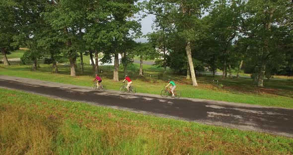 Aerial views of family bicycling along pastoral country roads.