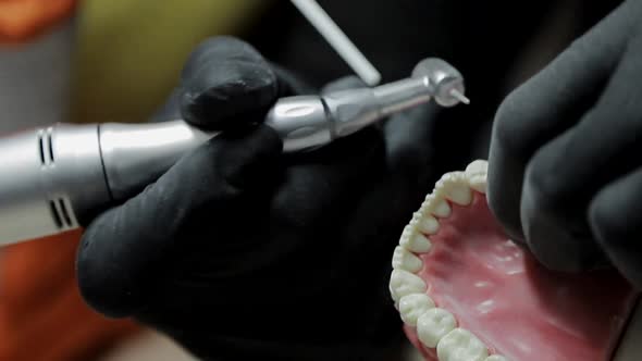 Close-up of a Dentist Practicing on a Mock-up of a Skeleton of Teeth Using a Drill Machine. the