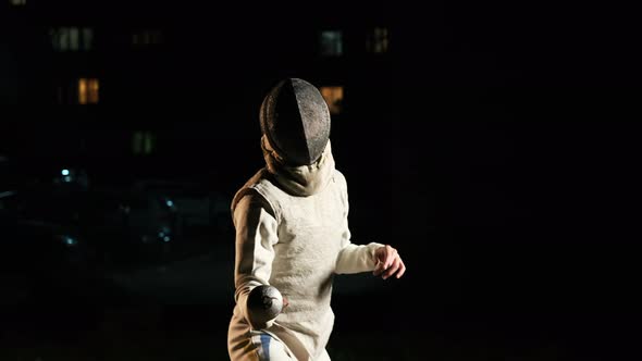 Young Fencer In The Dark Engaged In Fencing.