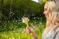 Closeup Of Young Woman Looking At Flying Dandelion Seeds - PhotoDune Item for Sale