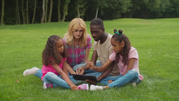 Diverse Family with Daughters Using Tablet Pc Outdoor