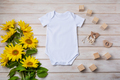 White baby short sleeve bodysuit mockup with yellow sunflowers, wooden toy - PhotoDune Item for Sale