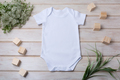 White baby short sleeve bodysuit mockup with green grass and white flowers - PhotoDune Item for Sale