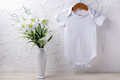 White baby short sleeve bodysuit mockup with lily bouquet - PhotoDune Item for Sale