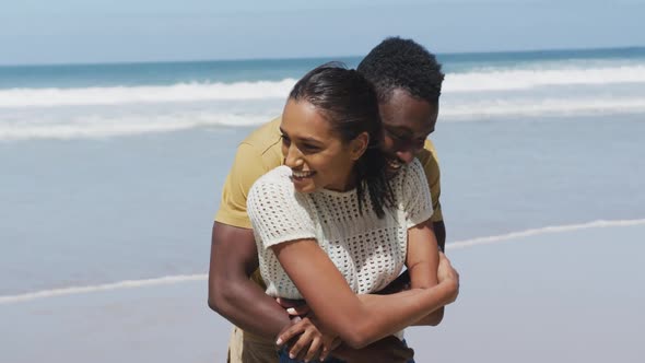 Happy african american couple hugging and embracing each other at the beach