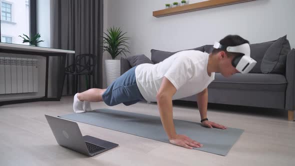 Young Man in Virtual Reality Glasses Performs a Workout and Pushups Sports Using Modern Technology
