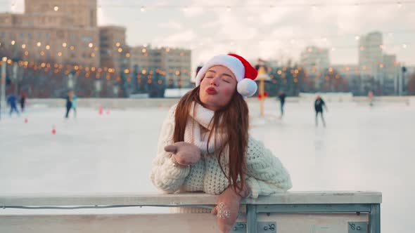 Young Smiling Woman Santa Hat Ice Skating Outside on Ice Rink Dressed White Sweater