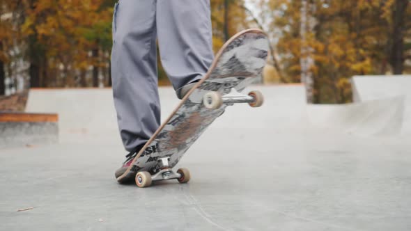 Skater Practicing in the Autumn Concrete Skate Park Making Tricks and Rides in Ramp