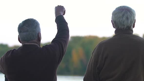 Two Friends Communicating Sitting on River Bank and Throwing Stones Into Water