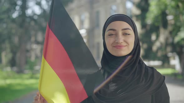 Portrait of Happy Smiling Muslim Woman Posing with German Flag on Sunny University Yard. Confident